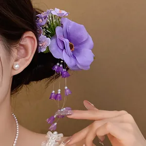Close-up detail of an elegant purple fabric flower hair clip with delicate pearl tassels