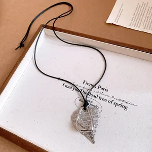 Detail view of a silver heart pendant necklace with embossed text on a black cord