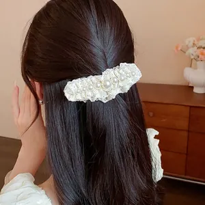 Elegant white lace hair clip with pearls worn on long wavy brown hair