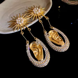 Dettaglio di eleganti orecchini a sole in oro con perle e ciondoli di cristallo