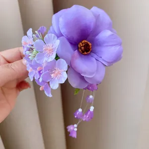 Close-up detail showing purple fabric flowers and delicate pearl tassels hair clip.