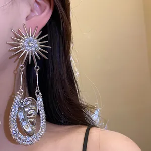 Dettaglio di un orecchino a sole argento con perle e pendente a forma di orecchio.