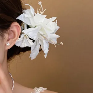 Detailed view of an ethereal white fabric flower hair clip with pearl decorations worn on bun
