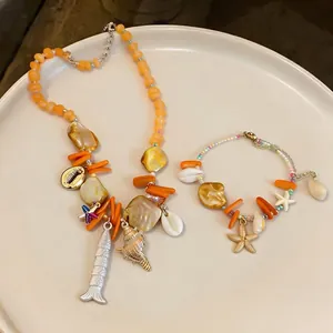 Urlaubs-Stil Muschel-Perlenkette und Seestern-Armband Schmuck-Set auf weißem Teller