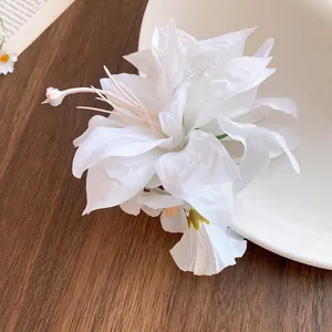 Detailed shot of elegant white fabric flower hair clip on a wooden surface