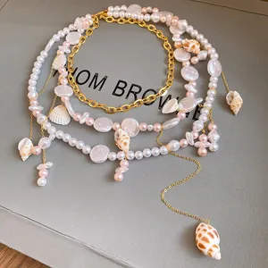 Dettaglio squisito della collana multistrato di perle e conchiglie con accenti di catena d'oro