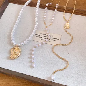 Detailed view of conch shell and pearl pendant necklaces on a wooden tray with linen background
