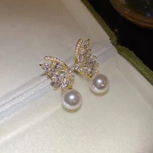 Close-up of elegant butterfly earrings with sparkling zircons and dangling pearls
