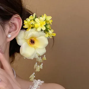 Exquisite detail of a yellow fabric flower hair clip featuring elegant pearl tassels