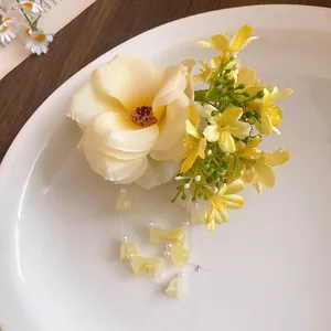 Detail showing yellow fabric flowers and delicate pearl tassels of a luxury hair clip.