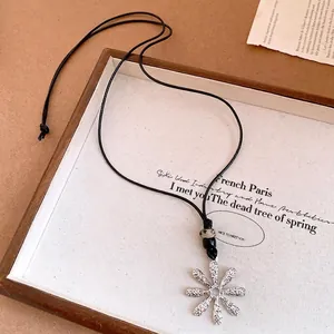 Close-up of silver flower pendant with fishbone texture and beaded black cord