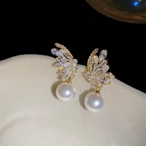 Detailed view of 18k gold plated zircon butterfly earrings with elegant white pearls