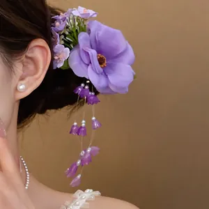Close-up detail of a purple fabric flower hair clip with elegant white pearl tassels