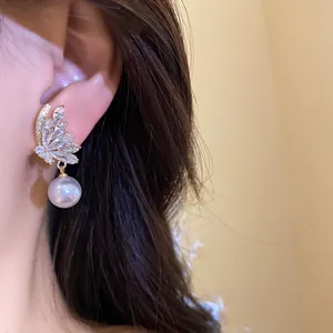 Close-up detail of 18k gold plated butterfly stud earrings with zircon and pearl drop