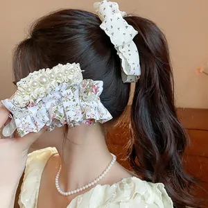 Detailed view of sweet floral ruffle and bow hair clips styled on a wavy ponytail.