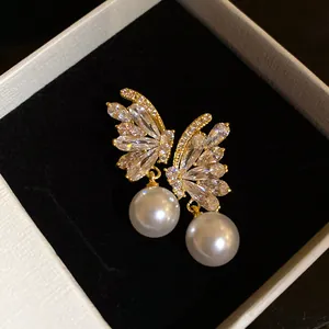 Detailed macro view of 18k gold plated butterfly earrings with zircons and pearls