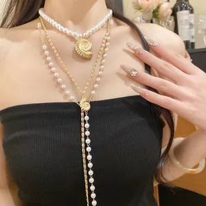 Close-up of layered pearl necklaces with golden conch shell pendants