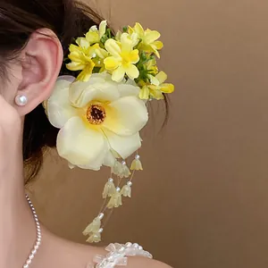 Close-up detail of a sweet yellow fabric flower hair clip featuring elegant pearl tassels.