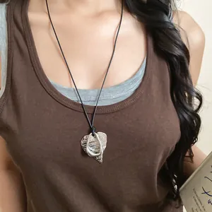 Detail shot of a silver heart pendant necklace on a black cord with French engravings.