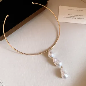 Detailed close-up showing three baroque pearls on a sleek gold-plated metal collar necklace