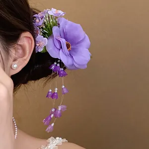 Detail of elegant purple fabric flower hair clip featuring dainty pearl tassels.
