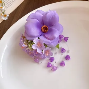 Close-up of elegant purple fabric flower hair clip with delicate pearl tassel accents