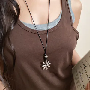 Detailed shot of a silver flower necklace with a patterned bead on a black cord accessory.