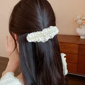Close-up view of an elegant white lace hair clip decorated with pearls on long hair