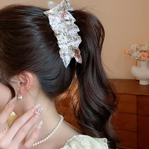 Close-up of elegant floral fabric hair clip worn on a ponytail with pearls