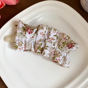 Close-up of elegant floral fabric hair clip with crystal and pearl accents.