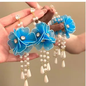Detail view of elegant blue fabric flower tassel earrings with pearls and zircons
