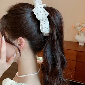 Detailed view of an elegant floral fabric bow hair clip styled on a high ponytail for women