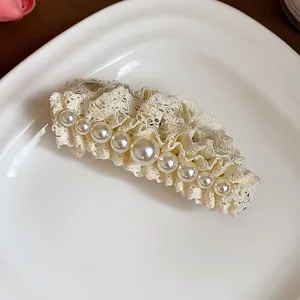 Close-up detail of cream lace hair clip with elegant pearl beads for stylish women