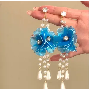 Detailed view of blue organza flower earrings with long pearl and crystal tassels.