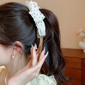 Detail view of a floral fabric bow hair clip worn on a elegant ponytail.