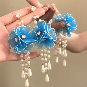 Detail shot of blue fabric flower earrings with crystal centers and pearl tassels