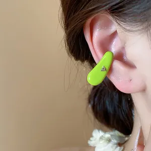 Detail view of a lime green oil-dripped ear cuff with a zircon on a model's ear.