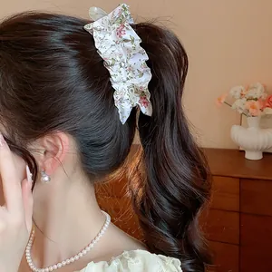 Elegant floral fabric bow hair clip detailed view on model's brunette wavy ponytail