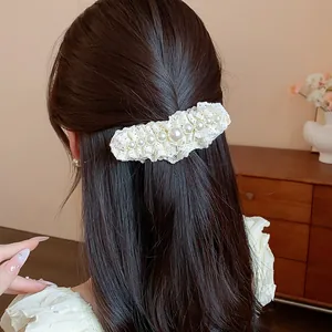 Close-up view of an elegant pearl and white lace hair clip styled on dark wavy hair