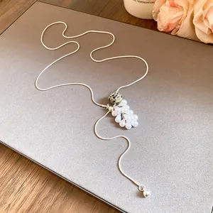 Detailed view of the teardrop pearl and spotted stone on a long silver necklace