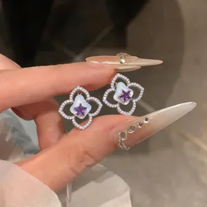 Detalle de pendientes de flor estrella estilo coreano con gema púrpura y circón
