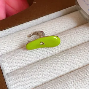 Close-up macro view of a vibrant neon green enamel ear cuff with a tiny zircon stone.