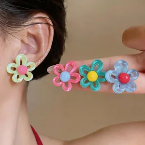 Gros plan de boucles d'oreilles en résine en forme de fleur colorée sur l'oreille