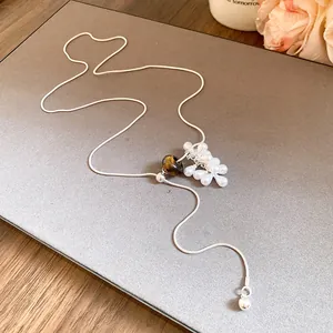 Close-up of teardrop pearl and tiger eye stone detail on silver drawstring necklace.