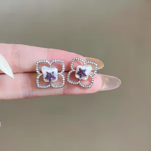 Primer plano de pendientes de plata con forma de flor, estrellas de circón púrpura y nácar