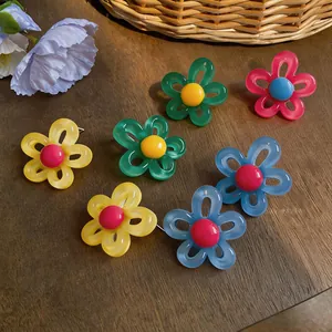 Boucles d'oreilles fleurs colorées style dopamine sur une surface en bois rustique