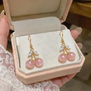 Detail shot of cherry-shaped earrings with pink cat-eye stones in a pink velvet jewelry box
