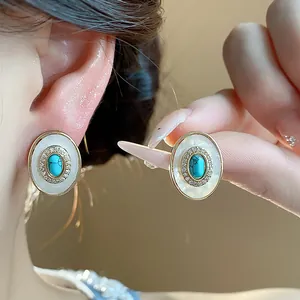Detail showing vintage oval shell stud earrings with turquoise stone and zircons.