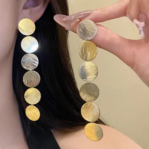 Detailed shot of long gold drop earrings featuring six brushed metal discs.