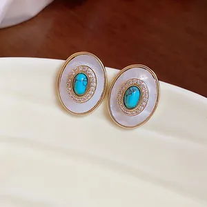 Close-up detail of elegant vintage oval stud earrings with turquoise and mother of pearl